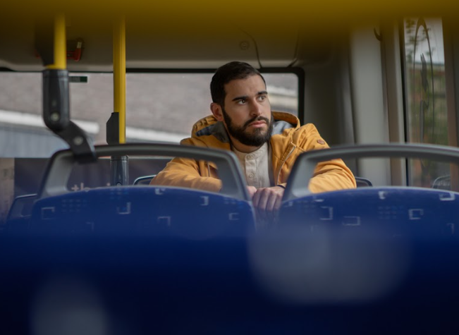 Een man zit in de bus en lijkt diep in gedachtes.